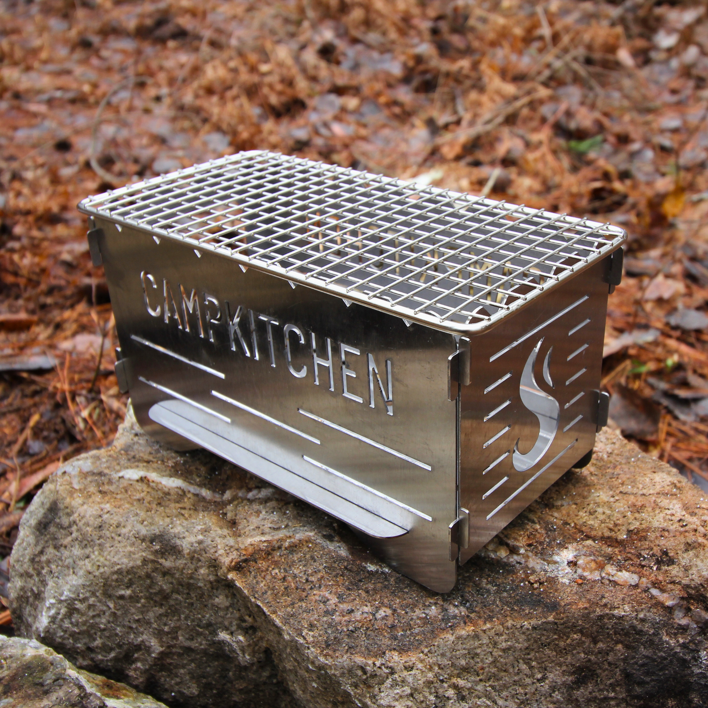 CAMPKITCHEN Twig Stove complete with the top grate on a rock.