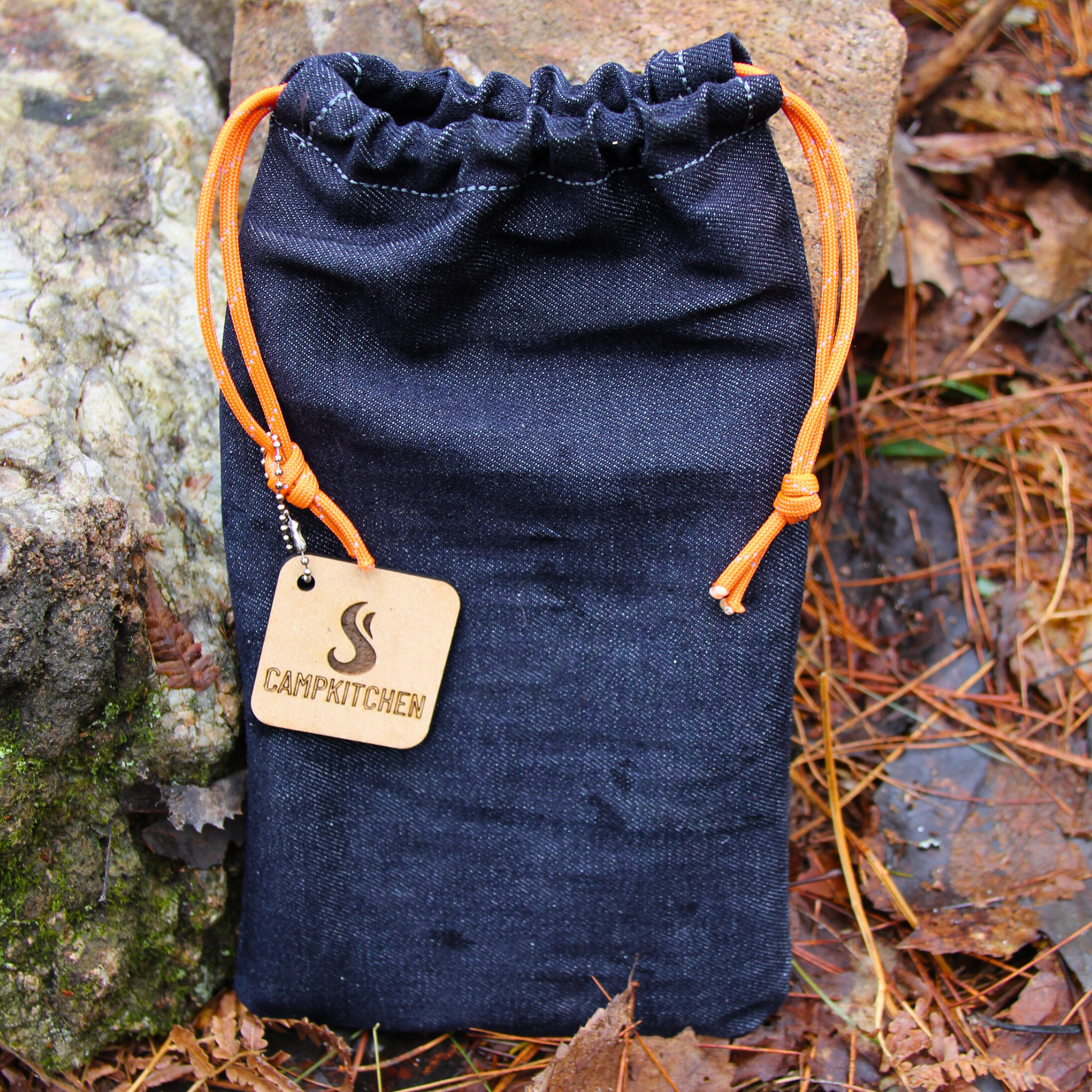 CAMPKITCHEN Twig Stove packed inside of a hand stitched denim bag equipped with paracord drawstrings.